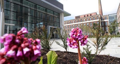 Exterior of the Theatre At The Mill with a flowerbed and pink flowers.