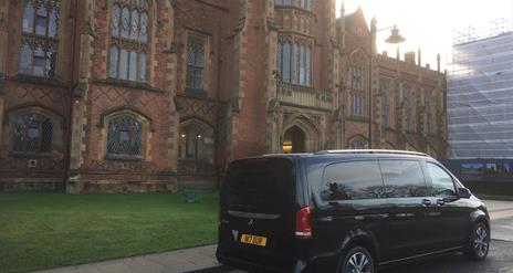 A black tour van parked outside Queens University's Lanyon building.