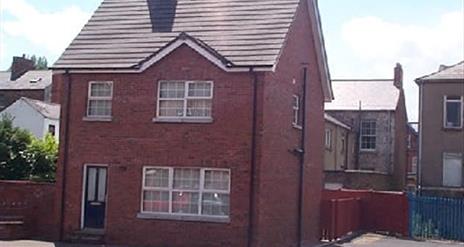 A photo of a dethatched red brick house.