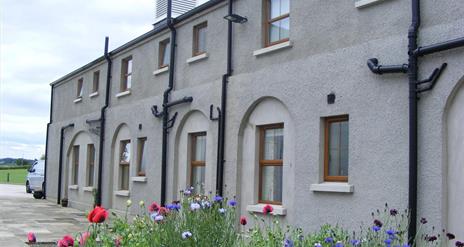 Image is of front of property with flower beds