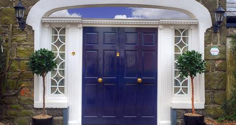 Large blue double doors decorated with lamps and potted trees.