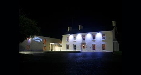 Image of a large two story building lit with four flood lights