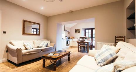 Image shows lounge area with 2 sofas, coffee table and wooden floor