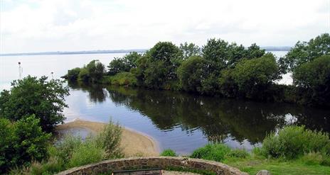 A stone area with a bench with a view at the end of the canal reaching the lough.