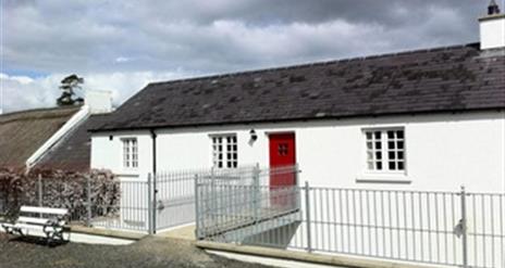 Outside of cottage with white exterior and red door