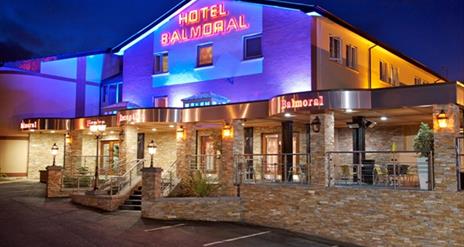 A photo of a hotel with an outdoor seating area lit up at night.