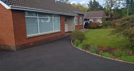 Driveway leading to a bungalow with a well-kept front lawn.