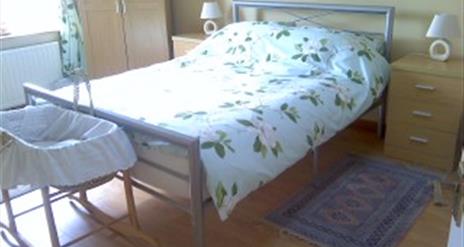 Double bed with bedside tables and baby moses basket