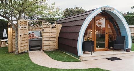 Glamping pod with hot tub beside enclosed with open gate