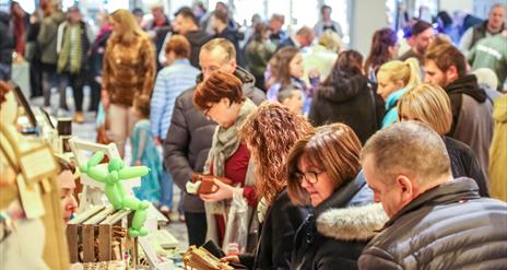 people browsing busy market stalls indoors