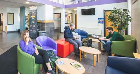 A photo of a communal lobby area with a group of people sitting together.