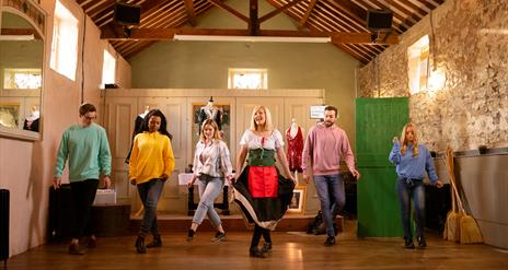 Group in a row with the instructor in front being taught Irish dancing as part of the Dancing at the Crossroads experience