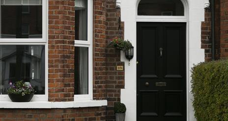 A black front door with a front window decorated with plants.