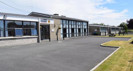 Image is of front of the building with tarmac driveway and grass area beyond