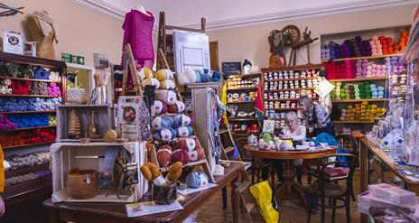 Interior of Lighthouse Yarns with lots of wool displays and people at the crafting table