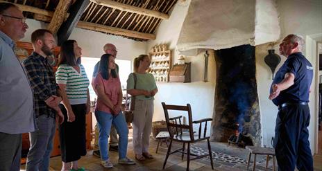 A group of visitors listening to the tour guide inside Andrew Jackson Cottage standing by the fire.