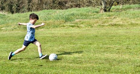 young boys kicks football at Newtownabbey footgolf