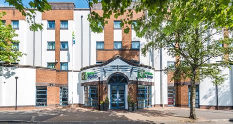 Photo of the exterior of the Holiday Inn Express Belfast City, Holiday Inn Express sign on the façade and trees on the sidewalk.