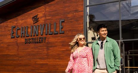 Couple walks outside the Echlinville Distillery in the sunshine