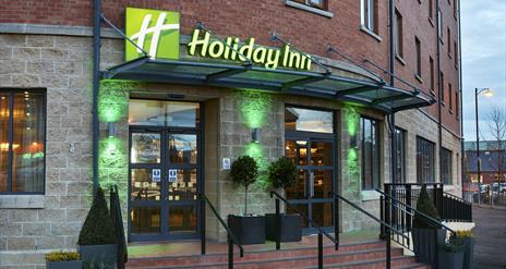 Photo of the entrance of the Holiday Inn Belfast City Centre. Holiday Inn sign above the doors. Stairs and ramp leading to the entrance doors.