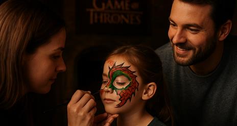 Woman painting a dragon on child's face as father watches.