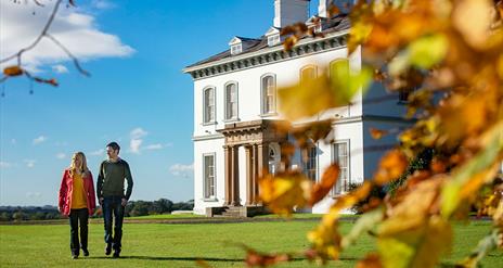 A couple walking through gardens of Ballyscullion park with the Georgian House in the background.