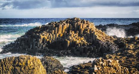 Waves crash against the stones of the Giants Causeway