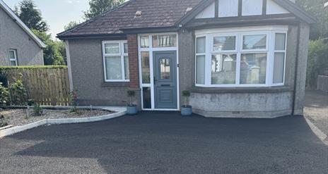 Detached bungalow with red hipped roof and private parking area and garden to front