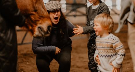 a family laughs and smiles around a horse