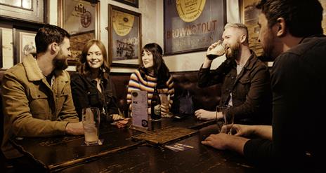 group of people at a table inside the bar chatting and enjoying drinks.