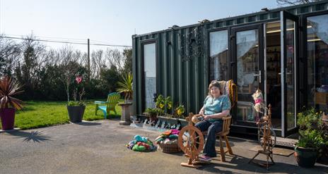 Christine using the spinning wheel outside of the Kiri Cottage Crafts workshop