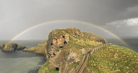 Picture of Carrick-a-Rede Rope Bridge with dark, moody grey skies and a rainbow