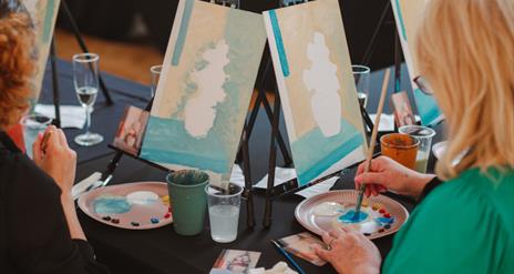 Image of a paint & prosecco session at the Ulster Museum showing two women painting canvases.