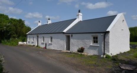 A traditional white country cottage at the roadside.