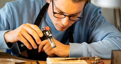 Man making jewellery holding a blowtorch as part of the jewellery making workshop with Gobbins Crafts in Islandmagee