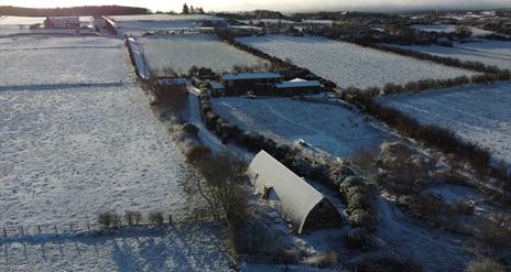 An aerial view of the studio on a Snowy winter day with the snow glistening on the curved roof.