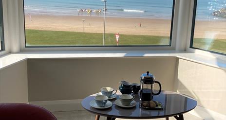 Seating area in front of window overlooking the beach and sea.