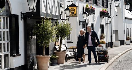 A couple pulling overnight bags entering into The Old Inn