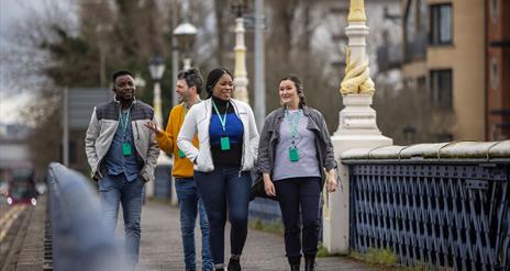 A tour group walking on the Queen's bridge in Belfast.