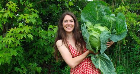 a woman holds a large cabbage