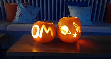 Two pumpkins craved, one with OM and the other with a planet and rocket