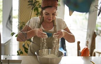 Image of one of the local producers Bronagh Duffin from Bakehouse NI sieving flour into a bowl