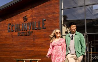 Couple walks outside the Echlinville Distillery in the sunshine