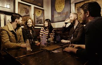 group of people at a table inside the bar chatting and enjoying drinks.
