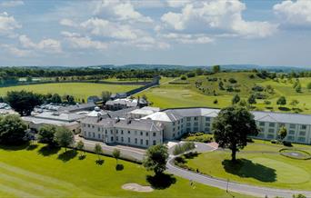 Drone view of the exterior at Roe Park Resort, fluorescent green natural surroundings and golf course.