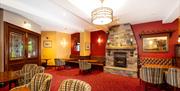 Red carpeted dining room with tables, chairs and a stone fireplace.