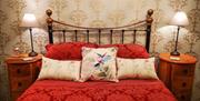 A red double bed with two bedside tables and cushions.