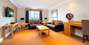 Lounge room with two sofas, coffee tables, a TV and a desk.