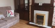 A living room with a sofa, cabinet and an electric fireplace.