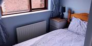 A single bedroom with a bedside table and an opened window.